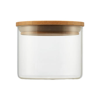 A clear, small cylindrical glass jar is shown with a round, light brown wooden lid resting on top. The minimalist design highlights the transparency of the glass and the natural texture of the bamboo lid.
