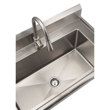 A close-up, high-angle shot shows a stainless steel utility sink with a gooseneck pull-out faucet. The sink is empty and features a centered drain with a strainer.