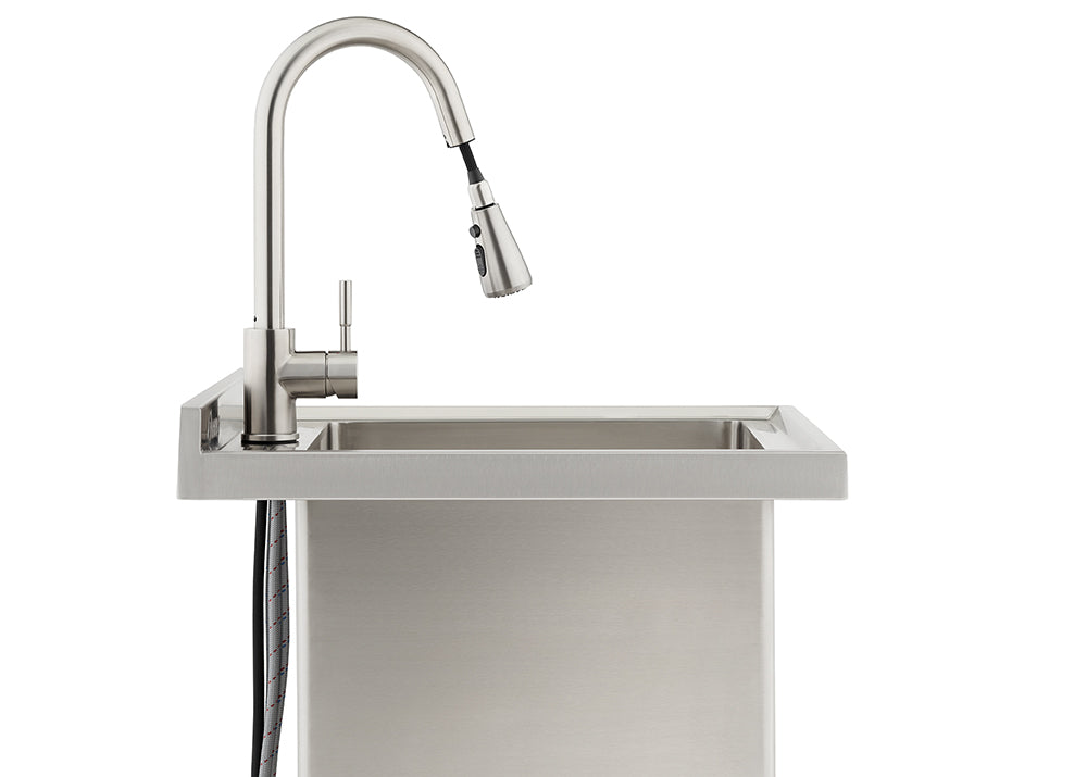 A profile view of a modern, brushed stainless steel kitchen faucet with a high-arc spout and pull-down sprayer mounted on a matching utility sink. The faucet's flexible supply lines are visible extending below the countertop against the sink's rectangular basin.