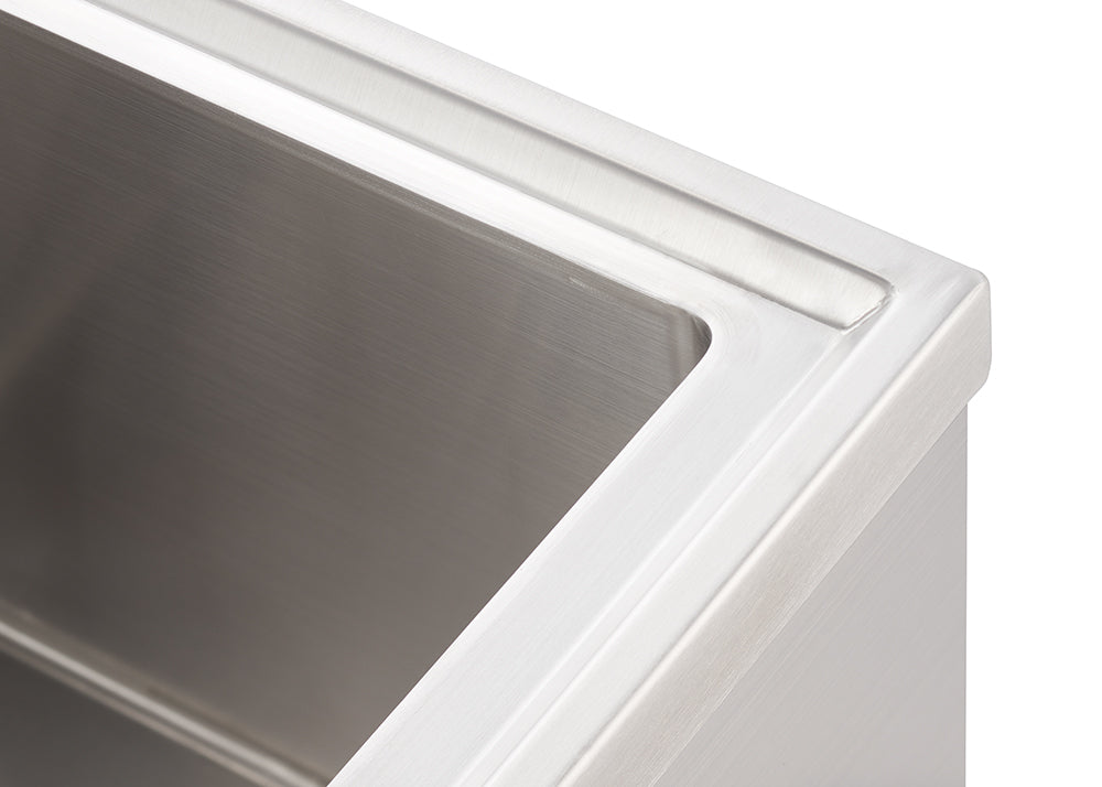 A close-up, high-angle shot shows the top right corner of a brushed stainless steel rectangular sink. The sink has crisp, clean lines and a subtle, polished sheen, suggesting a modern and functional design.