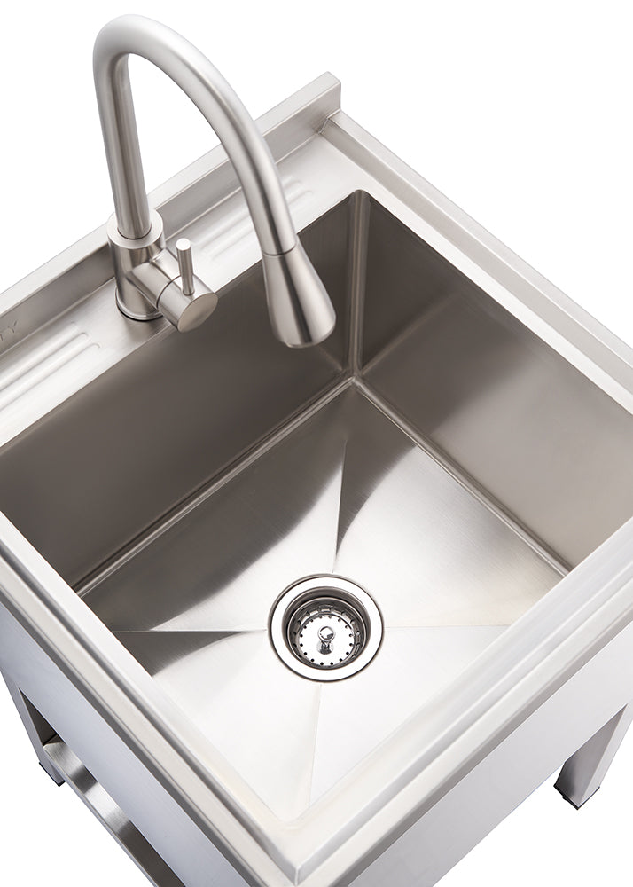 A high-angle shot shows a sleek, square-shaped stainless steel utility sink with a modern gooseneck faucet. The sink has a visible drain at its center, and the surface appears polished and reflective.