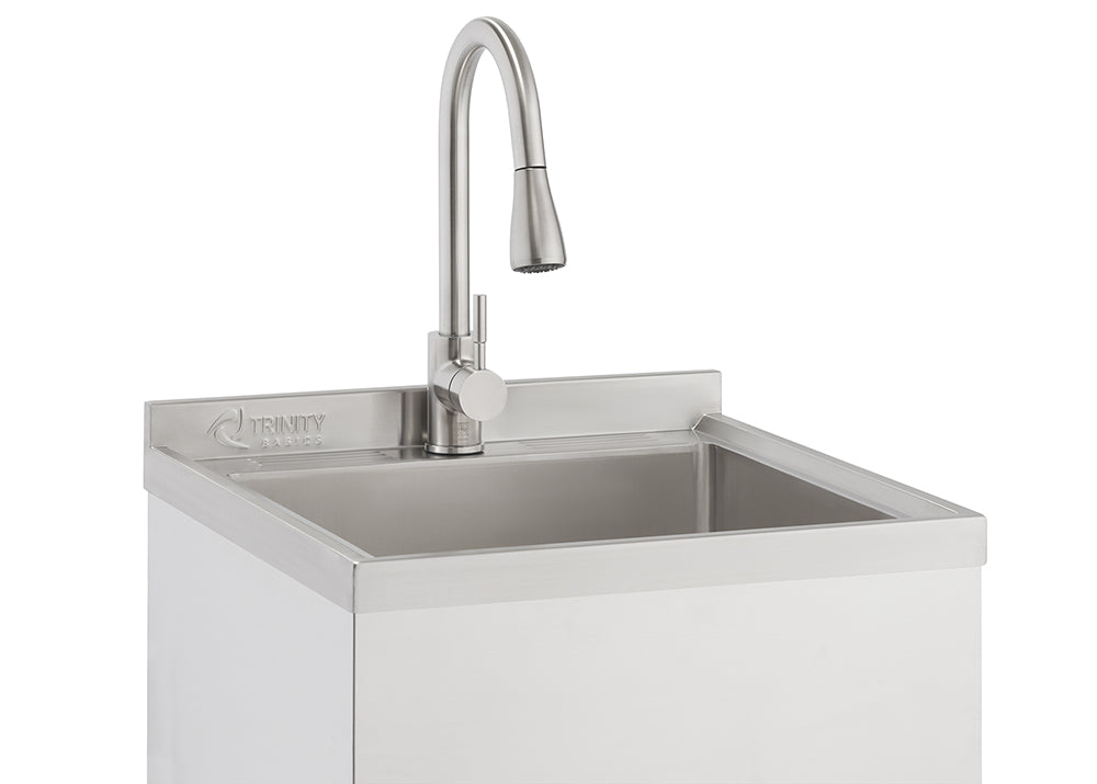 A close-up shot shows a stainless steel utility sink with a modern, brushed nickel gooseneck faucet. The sink cabinet is white, and the "TRINITY BASICS" logo is visible on the backsplash.