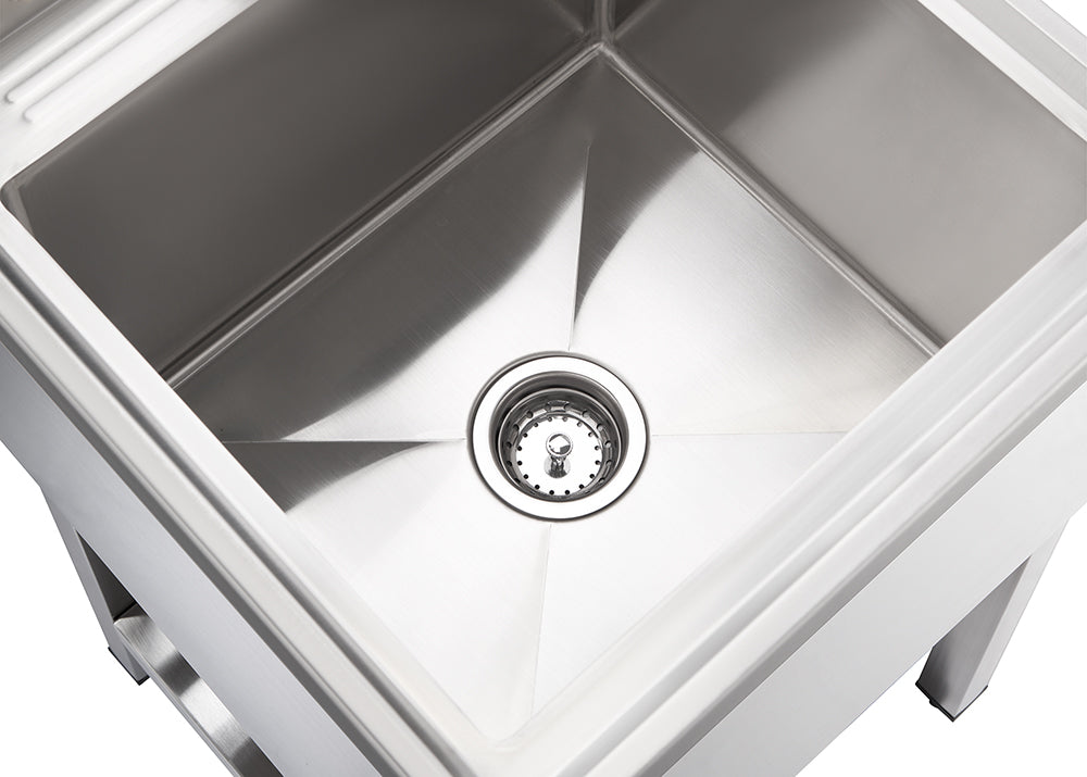A top-down, slightly angled shot shows a clean, empty stainless steel sink with a drain in the center. The reflective surface of the sink shows subtle light reflections, and a small portion of the sink's stand is visible at the bottom.