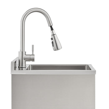 A sleek, brushed stainless steel gooseneck faucet with a pull-down sprayer is mounted on a matching industrial-style utility sink. The modern faucet features a single-lever handle and is set against a clean, white background.