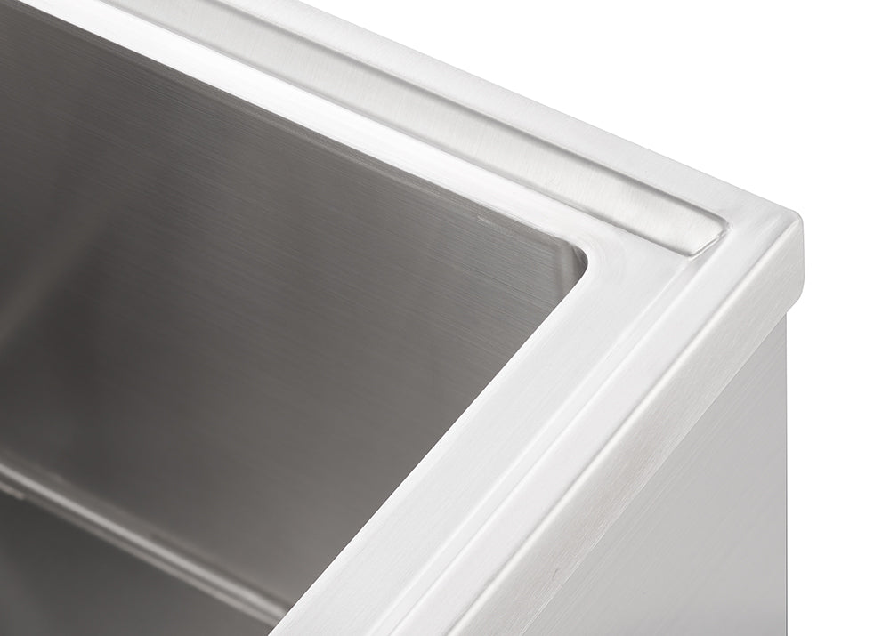 A close-up, high-angle shot shows the interior of a stainless steel sink, highlighting its brushed finish and clean lines. The top edge of the sink features a subtle, raised lip, and the inner corners are smoothly curved.