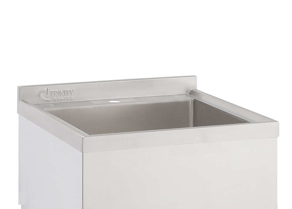 A close-up shot shows the top portion of a stainless steel utility sink. The sink features a rectangular basin and a backsplash with the "TRINITY BASICS" logo embossed on it.