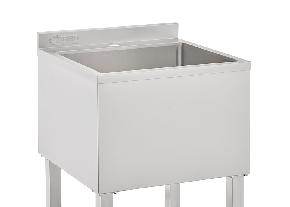 A close-up image of a square, stainless steel utility sink from the brand TRINITY BASICS. The sink is set on four metal legs and features a short backsplash with a single pre-drilled faucet hole visible.