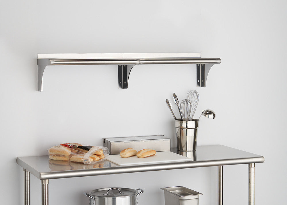 A stainless steel utility table with a lower shelf is shown in the foreground. A wall-mounted shelf with a backsplash is visible above, and various kitchen items are arranged on both surfaces.