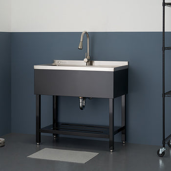 A stainless steel utility sink with a brushed metal faucet is centered in the frame, against a two-tone blue and white wall. To the right, a black wire shelving unit holds various cleaning supplies and a basket.