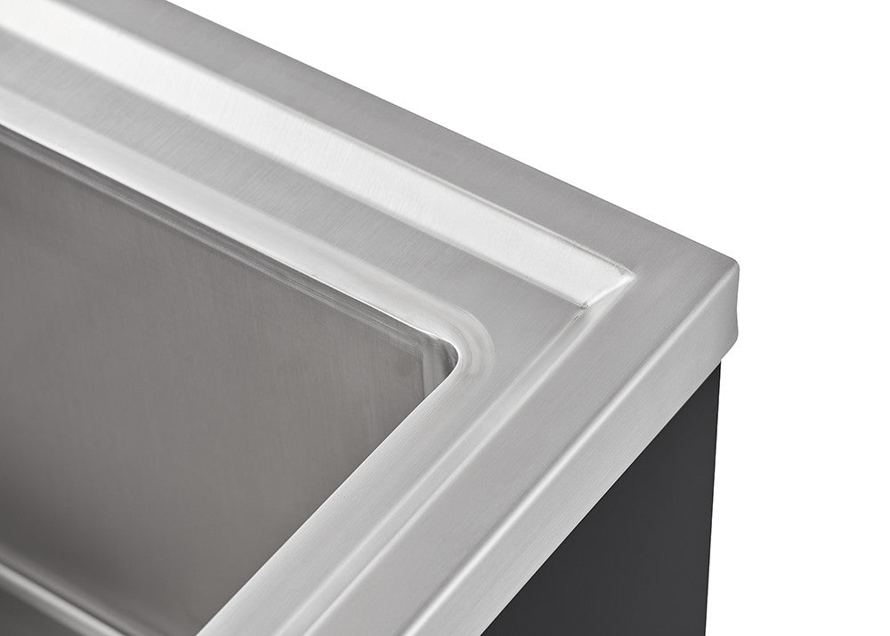 A close-up shot shows the corner of a stainless steel utility sink, highlighting the smooth, reflective surface and the clean lines of its design. The sink appears to be mounted on a dark surface, possibly a countertop or cabinet, which provides a stark contrast to the metallic sheen.