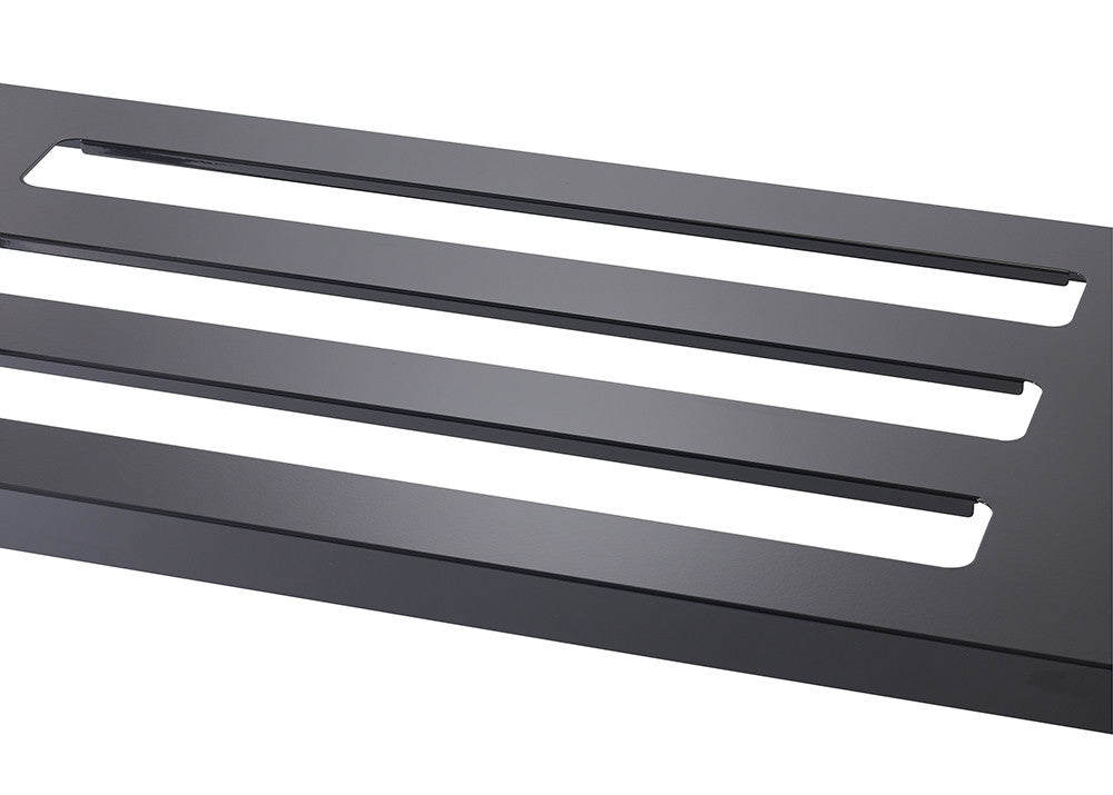 A close-up angled shot of a black metal surface with three evenly spaced rectangular cutouts. The metal has a smooth, matte finish and the cutouts reveal a lighter-colored surface beneath.