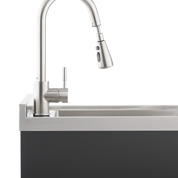 A modern, brushed stainless steel kitchen faucet with a pull-down spray head is mounted on a sleek, dark grey countertop with an integrated sink. The faucet's high-arc design and minimalist lever handle suggest contemporary style and functionality.