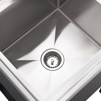 A clean, close-up shot shows the interior of a shiny stainless steel kitchen sink. The drain with a metal stopper is visible at the bottom center of the square basin.