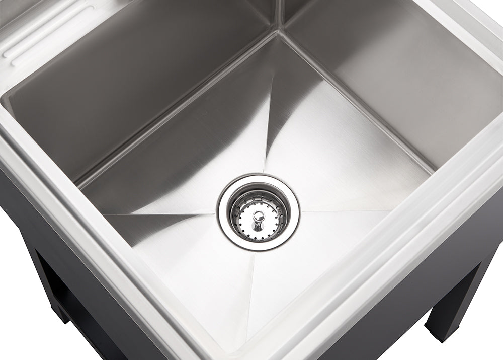 A clean, close-up shot shows the interior of a shiny stainless steel kitchen sink. The drain with a metal stopper is visible at the bottom center of the square basin.