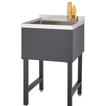 A tall, rectangular black utility sink with a stainless steel basin stands on four black legs. Two bottles of orange-labeled cleaning products are placed on the back edge of the sink.