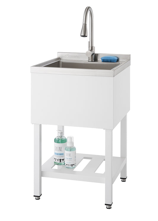 A modern, white utility sink with a stainless steel basin and a gooseneck faucet stands on white legs. A lower slatted shelf holds two bottles of cleaning solution, and a blue scrub brush rests on the edge of the sink.