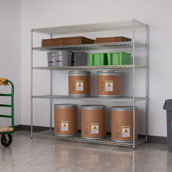 A silver, five-tier wire shelving unit stands against a light gray wall, holding various storage items. The shelves contain cardboard boxes, gray buckets, green bins, and large brown cylindrical containers with hazard labels.