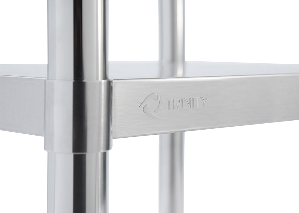 A close-up shot shows the stainless steel leg and shelf support of a Trinity EcoStorage table. The "TRINITY" logo is subtly embossed on the side of the support.