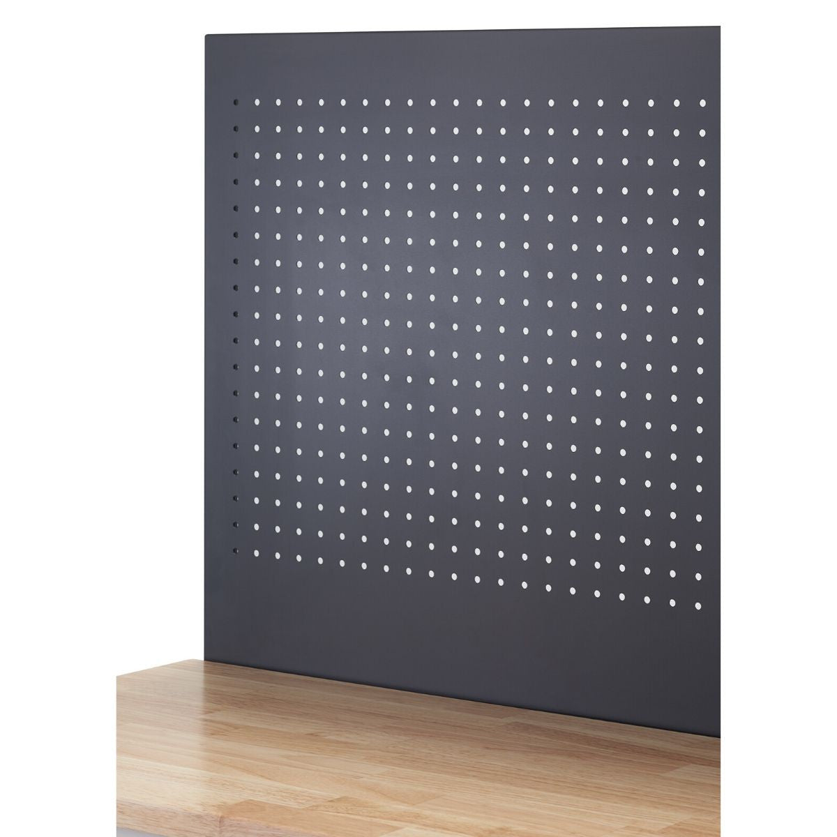 A close-up shows a section of a wooden workbench with a dark gray pegboard rising vertically from its surface. The pegboard is evenly perforated with numerous small, round holes arranged in a grid pattern.