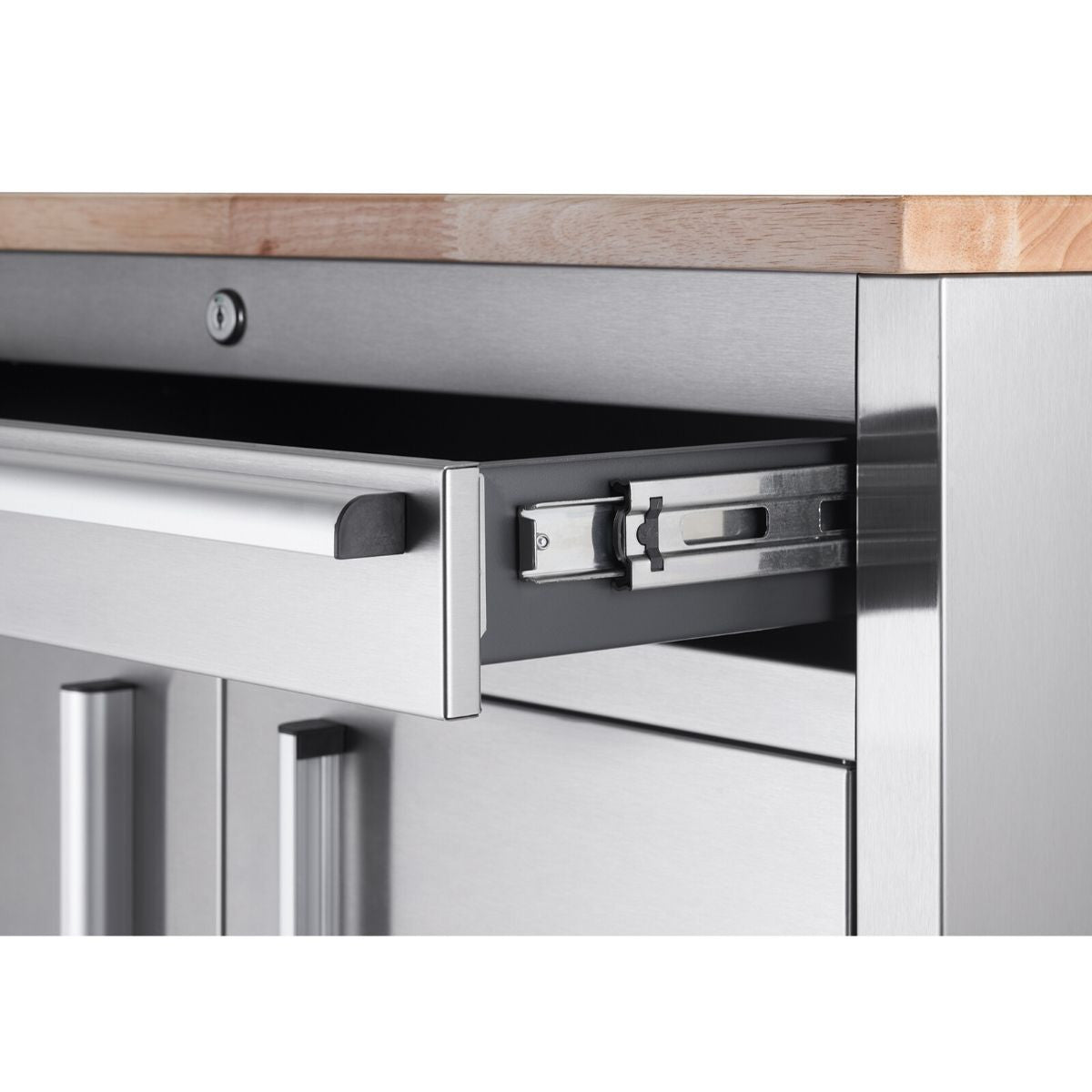 A close-up shows the partially open drawer of a stainless steel workbench. The drawer has a silver handle and reveals a smooth-gliding metal track.