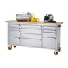 A silver metal workbench with a light-colored wooden top and orange wheels is shown against a white background. An air compressor, coiled yellow hose, motorcycle helmet, and black gloves rest on the workbench surface.