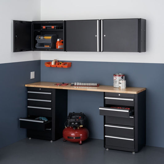 This is a well-organized garage space featuring a Trinity 6-piece garage cabinet drawer set in black with a wooden countertop. The set includes wall-mounted cabinets above a workbench with base cabinets and drawers on either side, providing ample storage and a functional workspace.