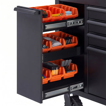 A close-up shot focuses on the pull-out side cabinet of a black tool workbench mounted on a heavy-duty caster wheel. The cabinet features three tiers of smooth ball-bearing slides holding vibrant orange organizer bins filled with small hardware, batteries, and supplies.