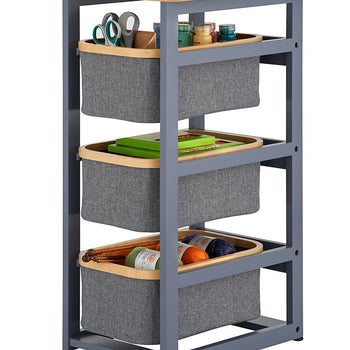 A three-tier storage organizer features a grey metal frame with a light wood top and three removable grey fabric baskets rimmed in wood. Each basket is filled with various craft supplies, including scissors, paint jars, books, and colorful yarn.