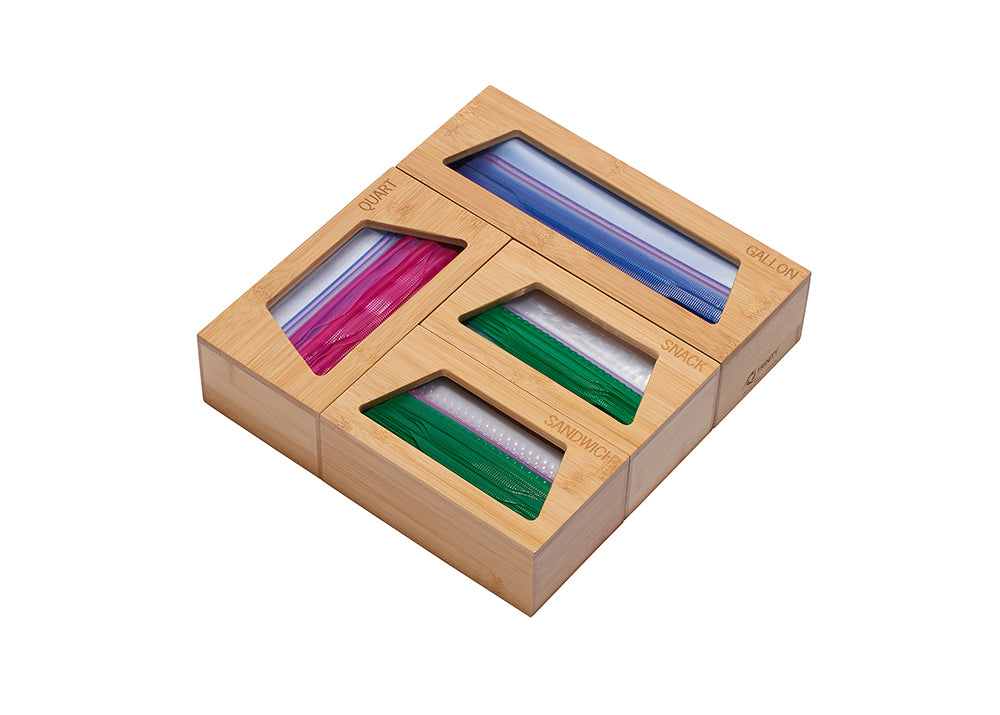 A light wood bamboo organizer for plastic bags is shown from an eye-level, slightly angled perspective against a white background. The organizer has four compartments labeled "GALLON," "QUART," "SNACK," and "SANDWICH," each filled with colorful zipper-top plastic bags.