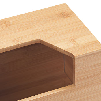 A close-up shot shows the corner of a light brown bamboo tissue box cover. The rectangular opening on top reveals the darker interior of the box.