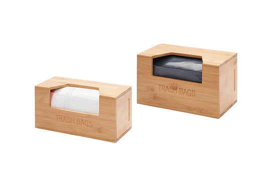 Two bamboo storage boxes labeled "TRASH BAGS" are shown, each containing a roll of trash bags visible through a cutout in the front. One box holds white trash bags with red ties, and the other contains black trash bags.