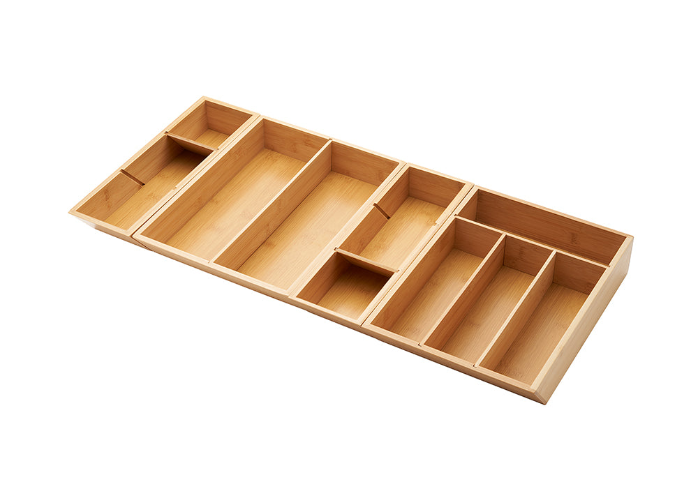 A bamboo drawer organizer is shown at a slight angle on a white background. The organizer is expandable and has multiple compartments of various sizes to hold utensils and kitchen gadgets.