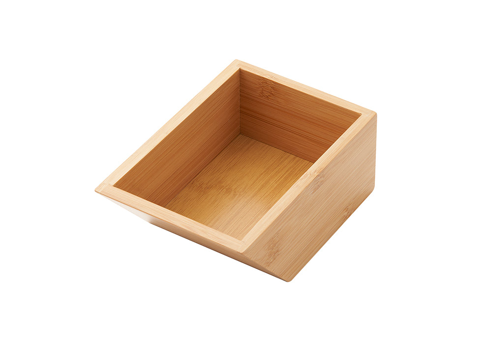 A light-colored, empty wooden box made of bamboo. The box has a slanted top opening, with the front side being lower than the back.