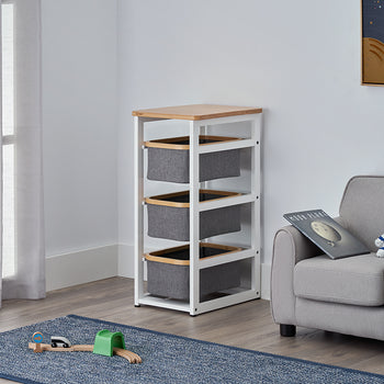A modern white storage rack with a wooden top and three grey fabric bins stands in the corner of a child's space-themed room. The setting includes a grey armchair with an astronaut plush, a blue rug with a toy train, and a solar system poster on the wall.