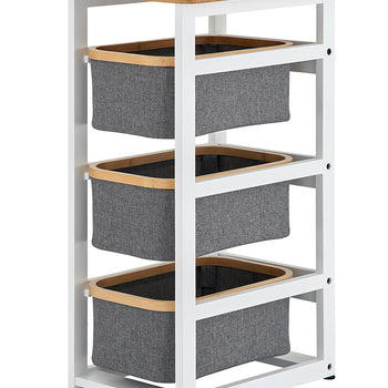 A three-tier white metal storage rack features a light wood tabletop and three removable gray fabric bins with matching wood trim. The minimalist organizer stands on small black feet and is designed for modern home or office use.