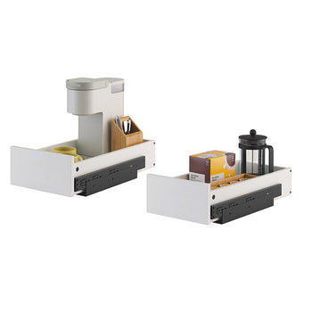 Two white pull-out cabinet drawers featuring black sliding mechanisms are shown against a plain white background. The left drawer holds a single-serve coffee maker and mug, while the right drawer is organized with a French press, coffee pod holder, and a box of coffee.