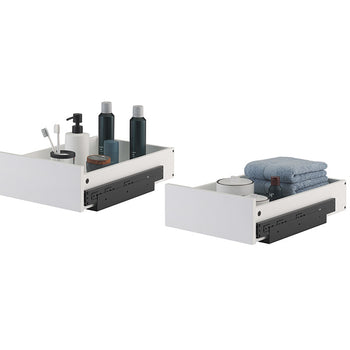 Two white, pull-out organizer drawers with black metal sliding hardware are displayed side-by-side against a plain white background. The left drawer holds toiletries including toothbrushes, soap dispensers, and dark bottles, while the right drawer contains folded blue towels and small bathroom containers.