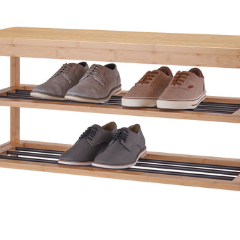 A long, narrow bench made of light-colored wood, possibly bamboo, doubles as a shoe rack. Two pairs of men's dress shoes and two pairs of casual sneakers are neatly arranged on the two slatted shelves beneath the bench seat.