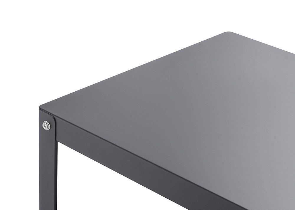 A close-up shot of the corner of a dark gray table against a white background. The table has a flat top and a thin, visible leg, with a small silver screw visible at the corner joint.