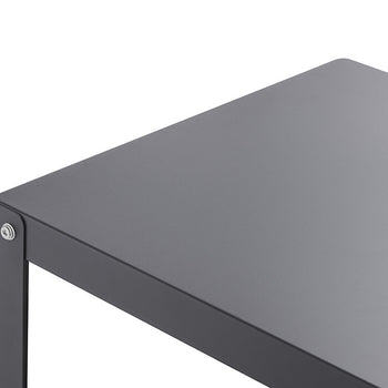 A close-up shot of the corner of a dark gray table against a white background. The table has a flat top and a thin, visible leg, with a small silver screw visible at the corner joint.
