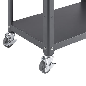 A close-up view of the bottom corner of a metal kitchen cart, highlighting two wheels with gray rubber tires and metal casters. The cart features a dark gray metal frame and shelf, with visible rivets connecting the legs.