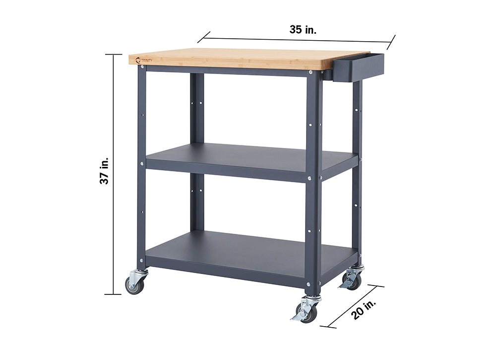 A front-facing view of a dark gray Trinity kitchen cart with a light brown bamboo top. The cart has two shelves below the top surface and is on four wheels, with dimensions of 37 inches high, 35 inches wide, and 20 inches deep.