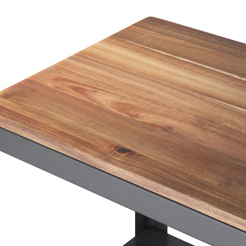 A close-up shot of a furniture corner, featuring a rich, reddish-brown wooden surface with visible grain sitting on a dark grey or charcoal metal frame. The smooth wood meets the angular metal structure, secured by a visible bolt in the upper left corner.