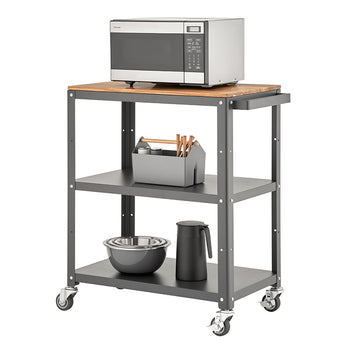 A three-tiered rolling utility cart with a dark gray metal frame and a light wood top shelf. A stainless steel microwave sits on the top, and the two lower shelves hold various kitchen items like bowls, a thermos, and a utensil caddy.