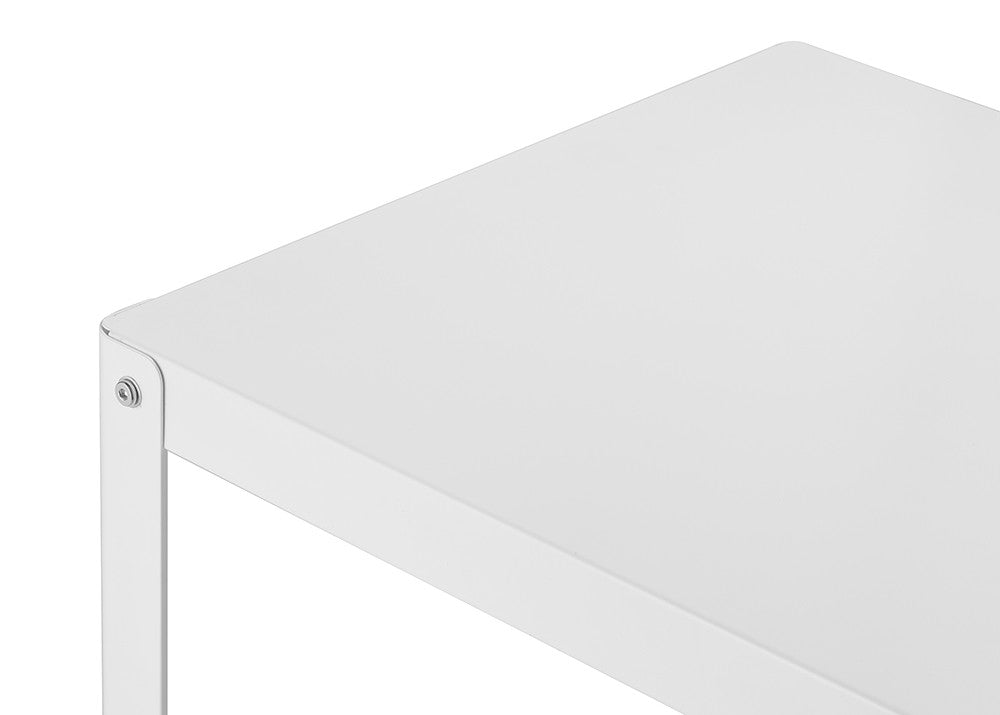 A close-up shot of the corner of a white metal table with a flat, smooth surface. The table's edge shows a thin metal frame and a screw holding the corner together.