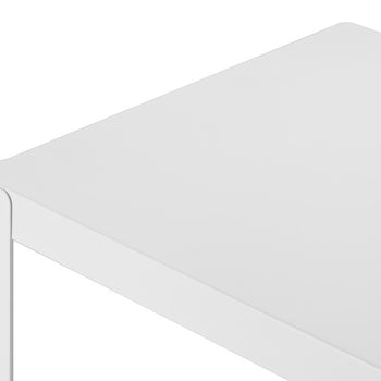A close-up shot of the corner of a white metal table with a flat, smooth surface. The table's edge shows a thin metal frame and a screw holding the corner together.