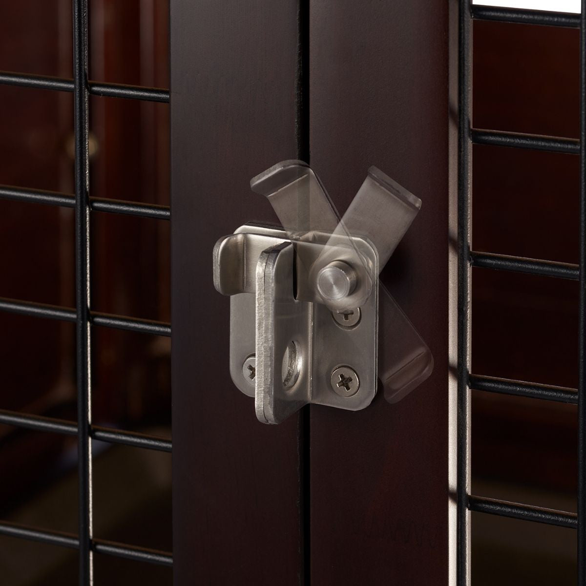 A close-up shows a silver, stainless steel slide gate latch affixed to a dark brown wooden door or gate. The latch is in a partially open position, with motion blur indicating its sliding mechanism.