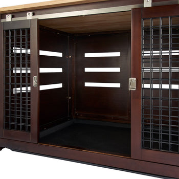 A close-up shot shows the open sliding doors of a dark brown wooden pet crate with black metal bars on the sides. The interior of the crate has a black mat on the floor and horizontal ventilation slots on the side walls.