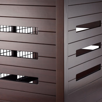 A close-up shows the slatted brown exterior of what appears to be a pet crate accent table. Rectangular openings on one side reveal a wire mesh interior, while the other visible side features longer, angled rectangular openings.