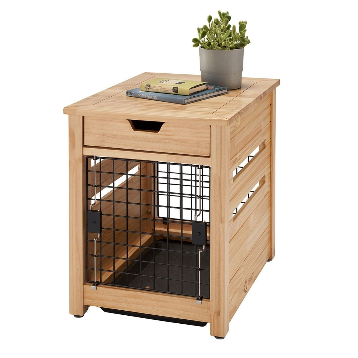 A light brown wooden pet crate end table with a black wire door and a drawer on top sits on a white background. A potted succulent, a book, and a notebook rest on the tabletop.